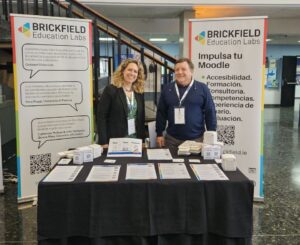 Laia and Jerry standing behind the Brickfield sponsor table with 2 pull up banners either side of them and leaflets on the table including a stack of Cardboard tip cubes.