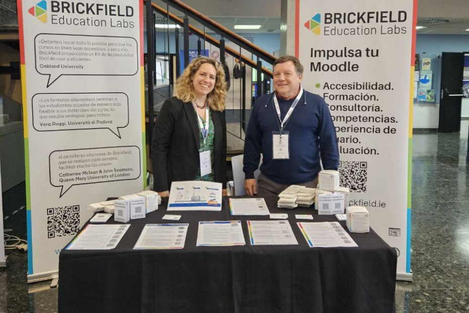 Laia and Jerry standing behind the Brickfield sponsor table with 2 pull up banners either side of them and leaflets on the table including a stack of Cardboard tip cubes.