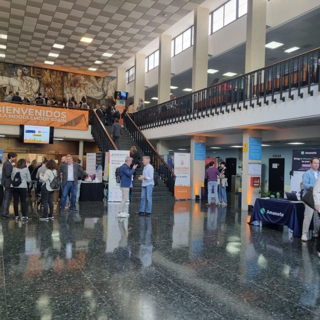 Coffee area at the Moodlemoot Spain - large foyer with exhibitor tables around it, people chatting and drinking coffee.