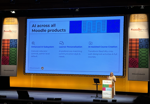 A large screen on a brightly lit stage displays the title "AI across all Moodle products" with three sections: Enhanced AI subsystems (granular educator controls, admin-level default), Learner Personalisation (AI preferences matching communication style and needs), and AI-Assisted Course Creation (transform files/URLs into well designed activities and full courses). Marie Achour from Moodle HQ stands at a podium to the right of the stage.