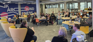 Attendees seated at Trinity Business School, Dublin, watching the expert panel discussion. The panel members are visible in the foreground seated facing the attendees: Gavin Henrick, CEO and Co-Founder of Brickfield Education Labs; Madeline Murray, National Coordinator at Oide Technology in Education; Rosa Doran, President and Founder of NUCLIO; and Alan Culbert, Deputy Principal of Edmund Rice College.