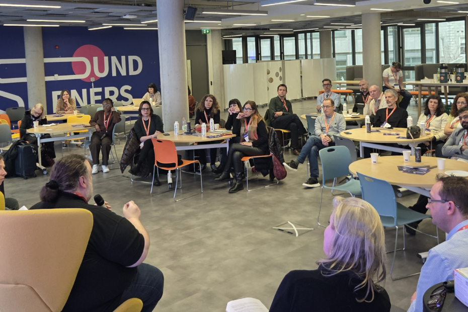 Attendees seated at Trinity Business School, Dublin, watching the expert panel discussion. The panel members are visible in the foreground seated facing the attendees: Gavin Henrick, CEO and Co-Founder of Brickfield Education Labs; Madeline Murray, National Coordinator at Oide Technology in Education; Rosa Doran, President and Founder of NUCLIO; and Alan Culbert, Deputy Principal of Edmund Rice College.