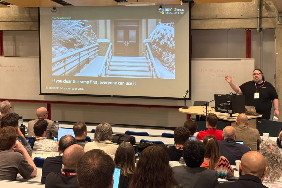 Gavin Henrick presents at MoodleMoot Canada, gesturing toward a projection screen showing a slide titled "The Paradigm Shift" from Brickfield Education Labs. The slide features a snow-covered building entrance with a ramp and stairs, captioned "If you clear the ramp first, everyone can use it.