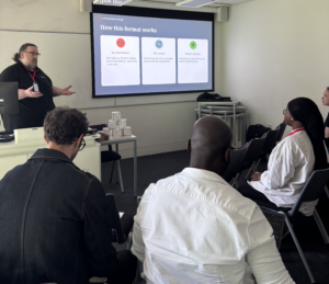 Gavin Henrick, CEO and co-founder of Brickfield Education Labs, presenting to a group of participants, with a slide titled 'How this format works' displayed on the screen behind him.